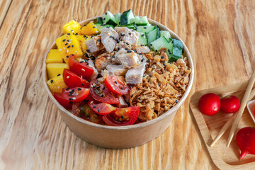 Takeaway chiken poke with mango and vegetables in recycled kraft paper packaging. Healthy Trendy