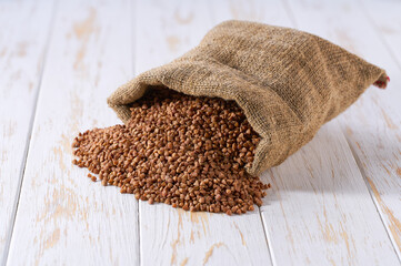 Raw buckwheat in sack on a light table, selective focus.