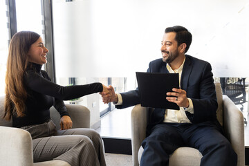 Two businesspeople shaking hands and greeting each other in an office