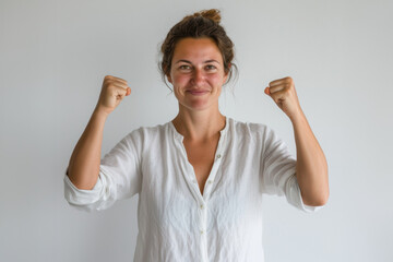 femme en chemise et veste levant les bras en l'air avec les poings fermés, heureuse et souriante, célébrant une victoire - obrazy, fototapety, plakaty