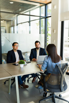 Rear view of a job candidate talking about her skills to a pair of male recruiters in a job interview