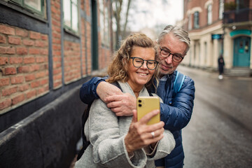 Senior couple taking selfie together in the city street