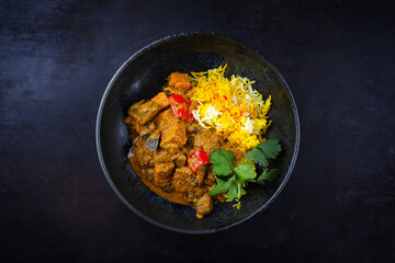 Traditional Indian vegetable curry with sweet potatoes, eggplant and saffron rice as top view in a Nordic design plate