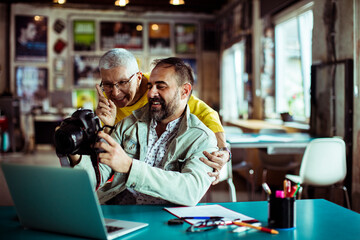 Man and woman reviewing photos on a digital camera in a creative office space