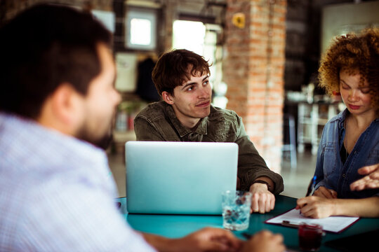 Team meeting with diverse group of professionals discussing project in a modern office