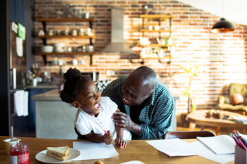 Laughing grandfather with granddaughter at kitchen table