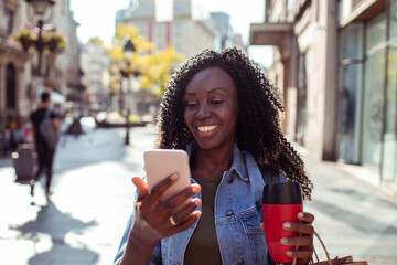 Smiling young woman using smartphone downtown