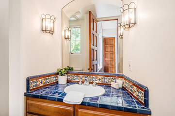 a blue sink and mirror in a bathroom with tiled counter tops