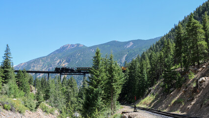 Vintage Georgetown train on old trestle.  Blue sky and green background for mountain gauge train.  Narrow gauge train.