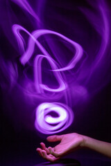 Long exposure shot of a hand playing with a glowing light