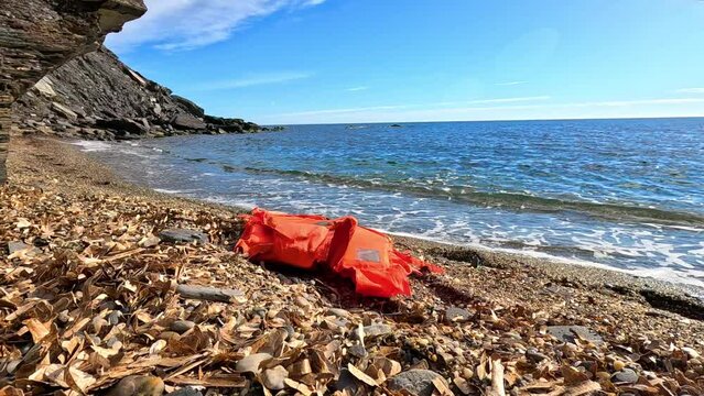 orange life jacket abandoned in the sand next to the beach shore