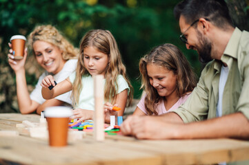 Two girls are building a tower with blocks while parents are smiling at them.