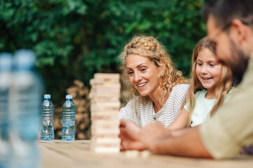 Cheerful family playing jenga game in nature.