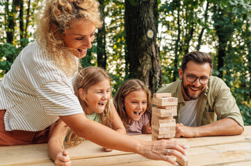 Family is playing fun wood block board game in nature.