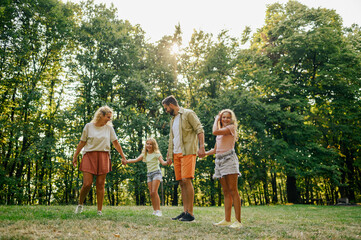 Fototapeta premium A cheerful family holding hands and spending free time in nature.