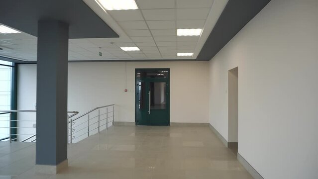 An empty spacious room of a modern office building with large windows. An empty hall with columns and a new renovation. Interior design. Suspended ceiling and square LED lamps.