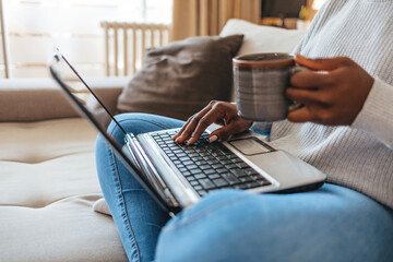 Woman, coffee and video call on laptop in home for group communication, internet and chat. Happy African female person saying hello on computer for virtual conversation, online contact and webcam. © Jelena Stanojkovic