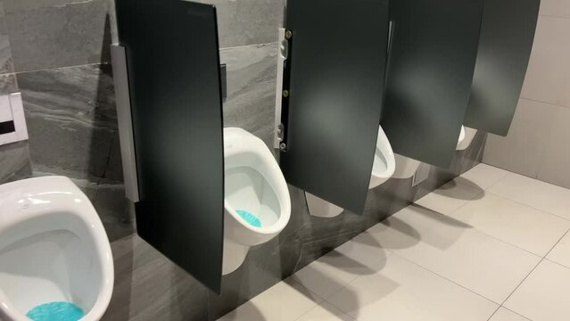 Rows of modern urinals with a sensor WC flush in a public men's room