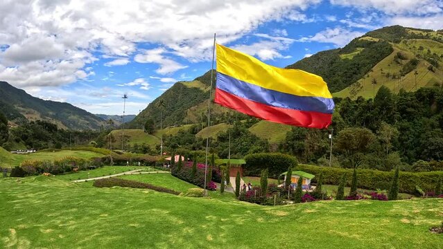 Colombian flag waving on the vally of cocora in salento, quindio, colombia, next to the palm trees and green grass
