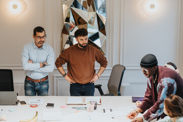A multiethnic team of company employees collaboratively discuss strategy in a well-lit modern...