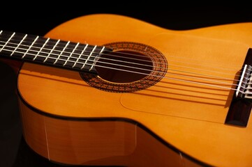 Classical Spanish flamenco guitar close up, dramatically lit isolated on black background with copy space.