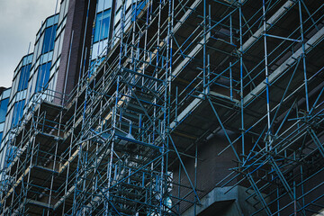 Complex network of metal scaffolding on the exterior of a modern building under construction in...