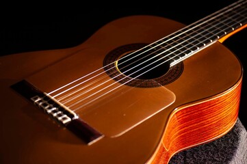 Classical Spanish flamenco guitar close up, dramatically lit isolated on black background with copy...
