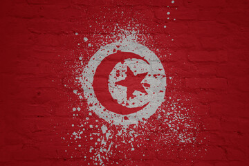 colorful painted big national flag of tunisia on a massive brick wall