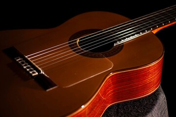 Fototapeta premium Classical Spanish flamenco guitar close up, dramatically lit isolated on black background with copy space.