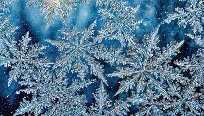 A close up of snowflakes on a blue background. The snowflakes are all different shapes and sizes, and they are all very close together. The image has a peaceful and serene mood