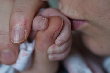 Close-up of a newborn baby's tiny hand gripping an adult's finger, symbolizing care and family...
