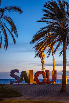 colorful letters of Salou town, palm trees andl beach at sunset, Catalonia, Spain