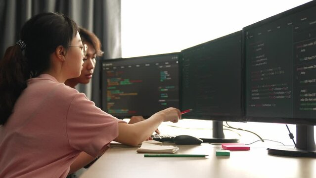 Slow motion back end software developer engineer for computer programming working together on debugging writing computing code, solving complex algorithms display on monitor in office. Burgeoning
