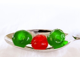 Green and red candied fruit or glacé fruit on a white background with copy space