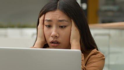 Exhausted overworked Asian woman girl student studying online work on laptop in office hold head headache tired chinese korean female employee businesswoman upset job failure despair fatigue burnout