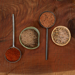 kinds of spices in small bowls and spoons on a wooden background