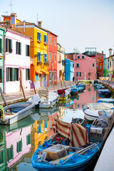 Fototapeta na wymiar Burano island. Beautiful colored houses, canal with blue boats on water. Sunny day in the city. no peoples.