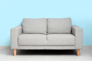 Zelfklevend Fotobehang Cozy grey sofa near blue wall © Pixel-Shot