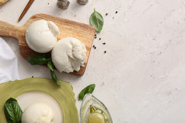 Wooden board and plate of tasty Burrata cheese with basil on white background