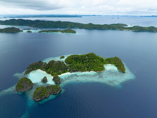 Rock islands, surrounded by coral reef, rise from Raja Ampat's tropical seascape. This region of...