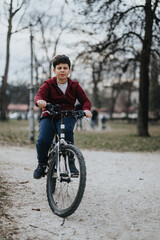 A young boy experiences the joy of childhood as he rides his bicycle along a park path outdoors, showcasing activity and youth.