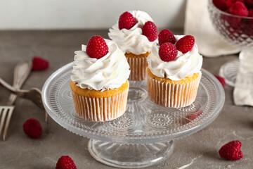 Stand with tasty raspberry cupcakes on table