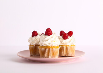 Plate with tasty raspberry cupcakes on grey background
