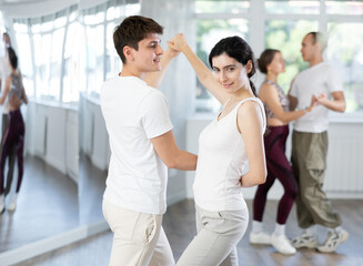 Girl paired up with young man, they train to perform social hustle dance, rehearse performance....