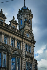 Vintage clock tower on an old European-style building against a cloudy sky in Leeds, UK.