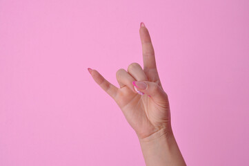 mão feminina com alongamento em fibra de vidro nas unhas fazendo sinal simbolo
