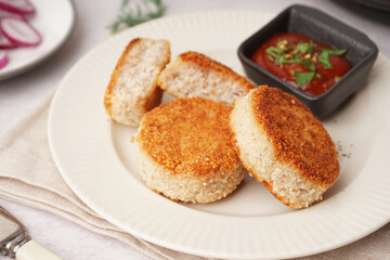Plate with tasty meat cutlets and sauce on white background