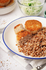Plate of tasty meat cutlets with buckwheat on white background