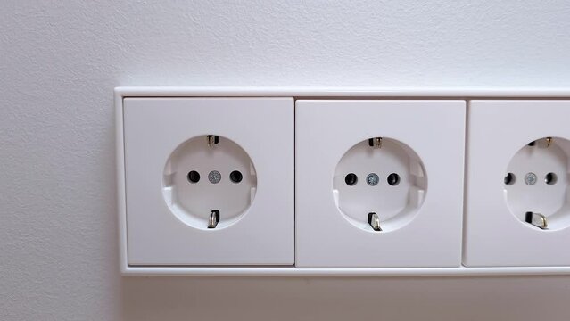 Three white european power outlets in a row installed on a clean white wall with no plugs inserted