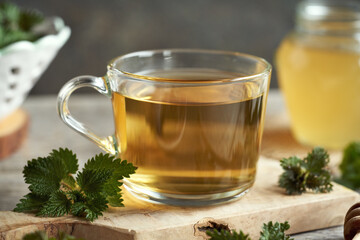 A glass cup of herbal tea with fresh stinging nettles